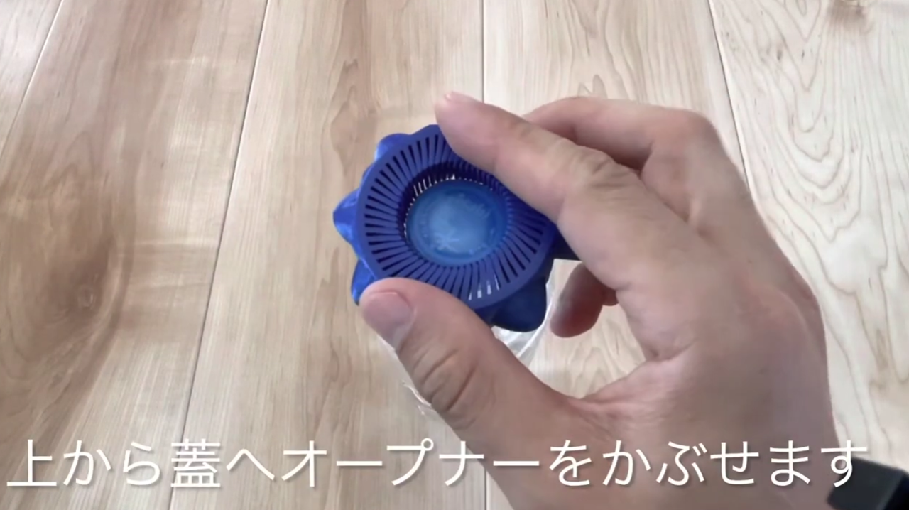 動画を読み込む: 上から蓋へオープナーをかぶせます。次に、硬いときは長い柄を壁に押し当てます。あとは親指でクルクル回します。